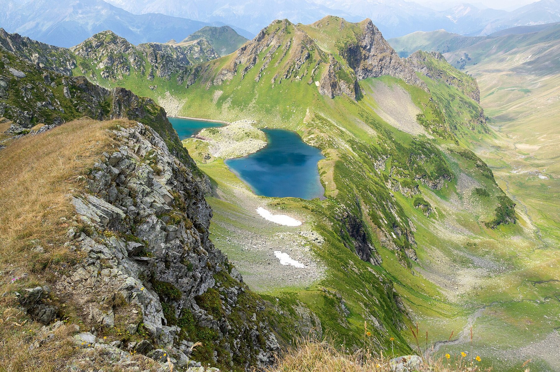 Green slopes and rocky ridges above two mountain lakes